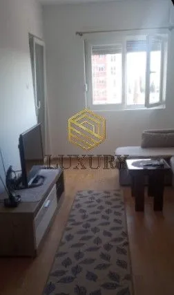 Dnevna soba sa garniturom, TV komodom i prozorom.
