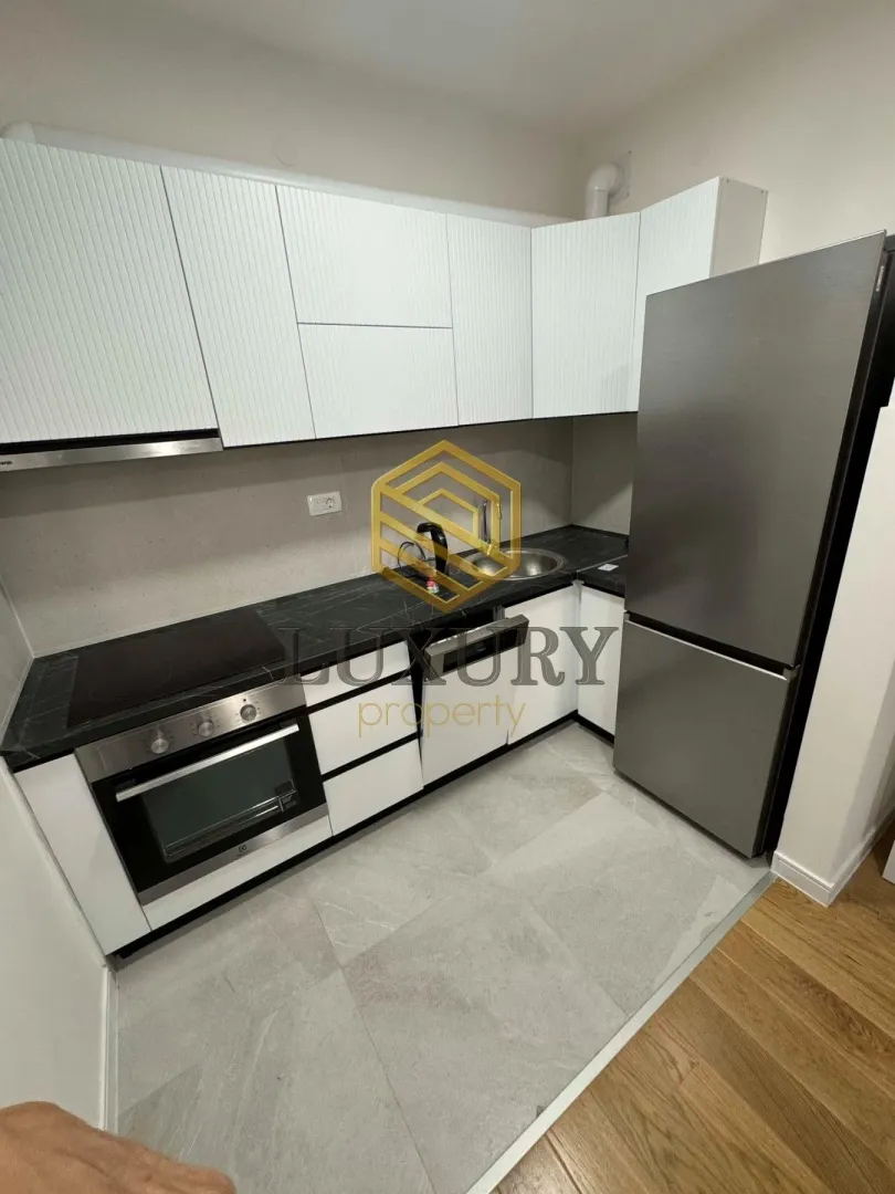 Small kitchen with white cabinets, built-in oven, and refrigerator.