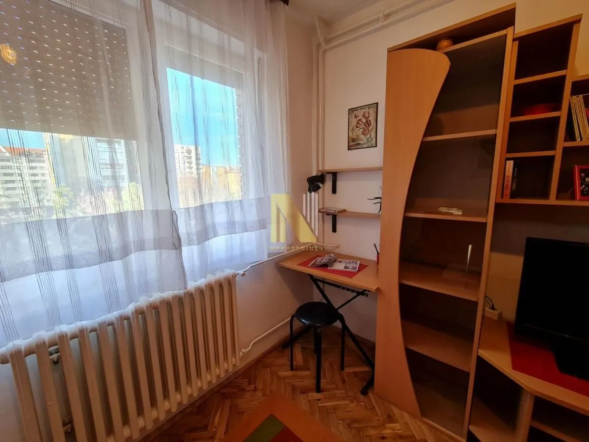 Manja soba sa radnim stolom, policama i prozorom.