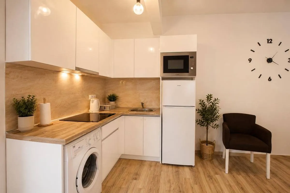 Modern white kitchen with a wooden countertop and built-in appliances.