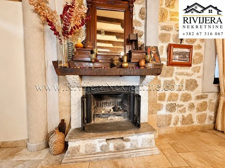 Close-up of a traditional stone fireplace with a wooden mantel and decor in the living room.