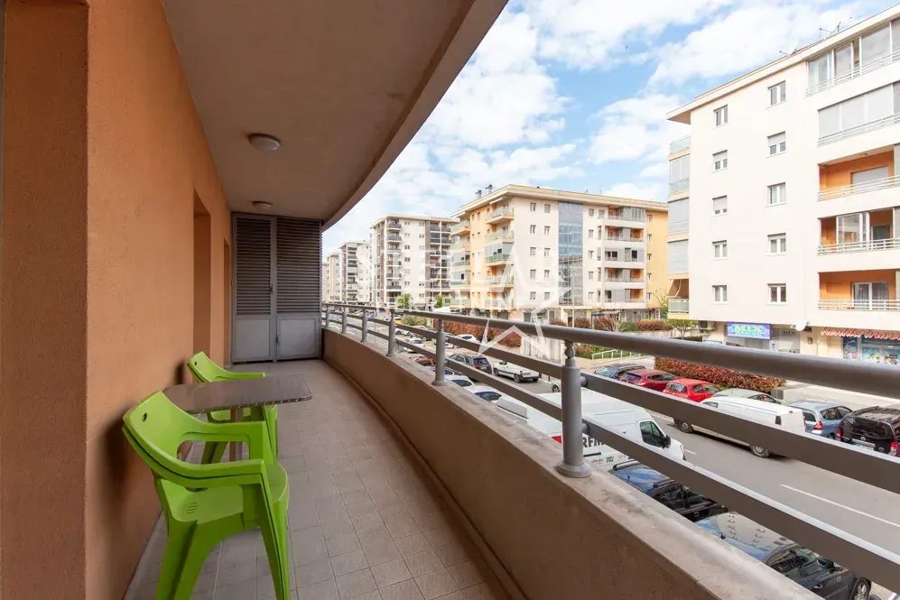 Covered balcony with seating set and street view.