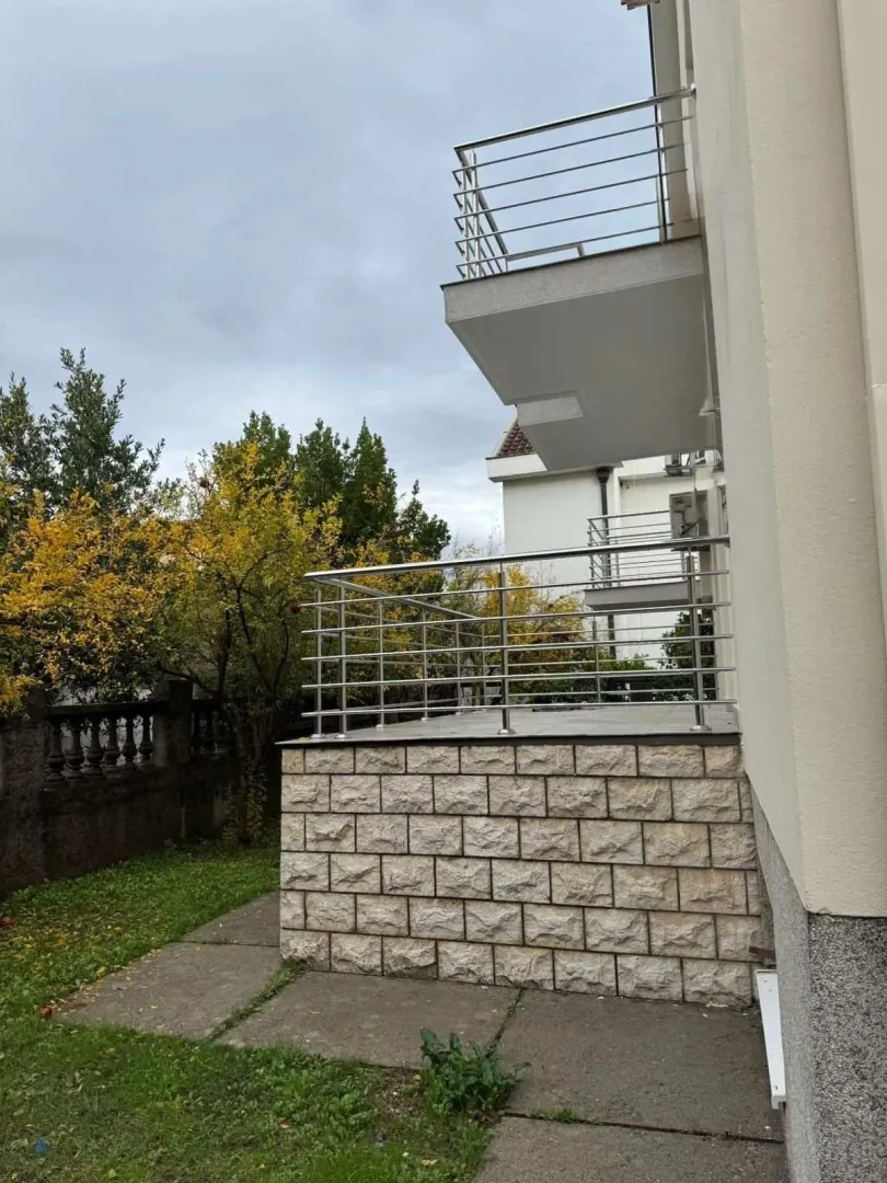 Exterior view of a modern building featuring a paved terrace with metal railings.