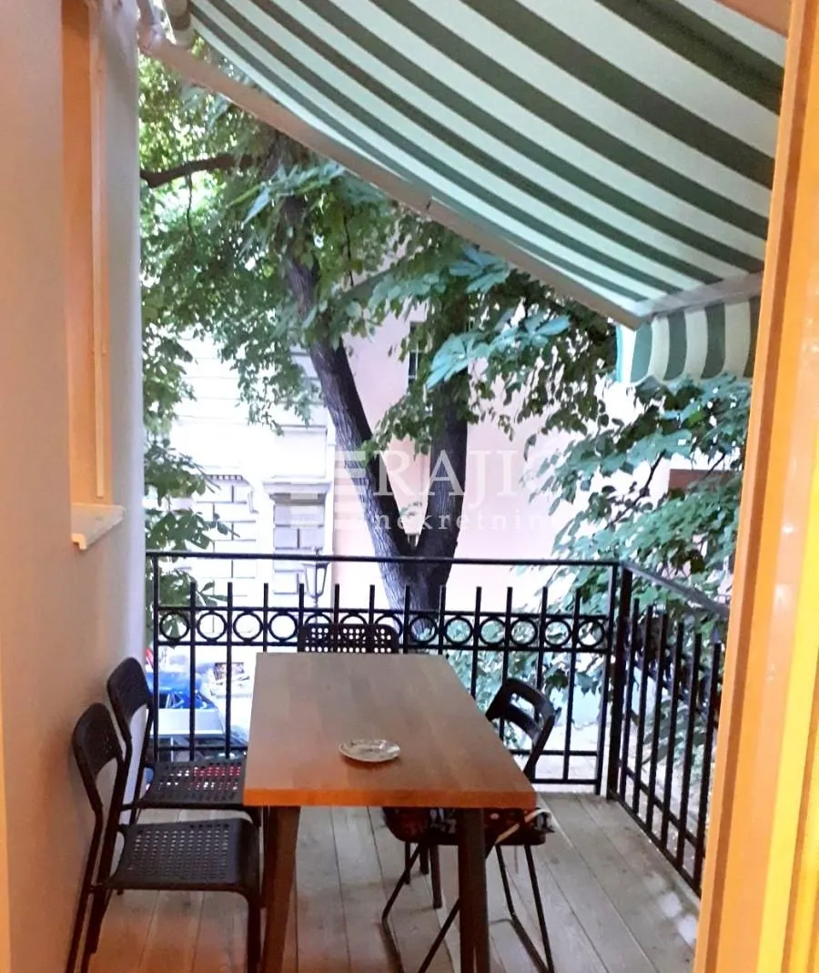 Furnished balcony with a table, chairs, and an awning.