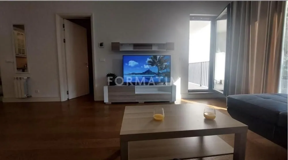 Dnevna soba sa televizorom, drvenim stočićem i izlazom na terasu.
