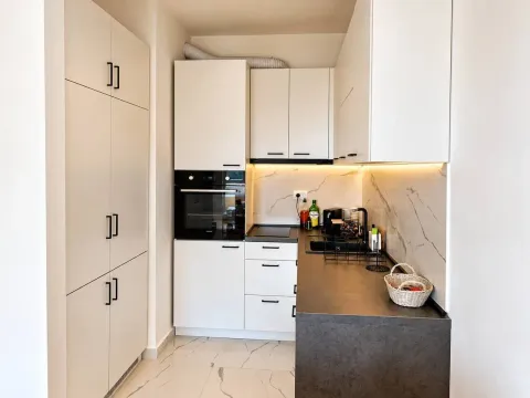 Modern white kitchen with dark countertops and built-in appliances. - image 5