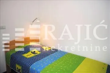Smaller bedroom with a bed and a wall lamp.