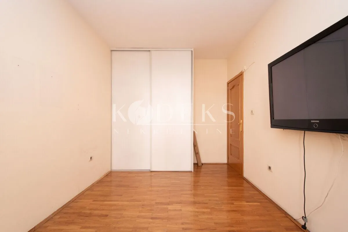 Empty bedroom with a built-in wardrobe and a wall-mounted TV.