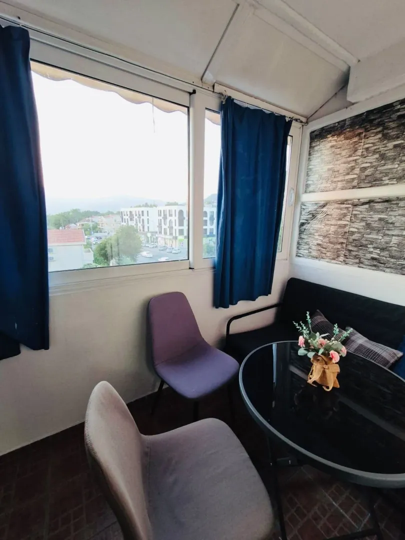 Enclosed balcony with seating furniture and a city view.