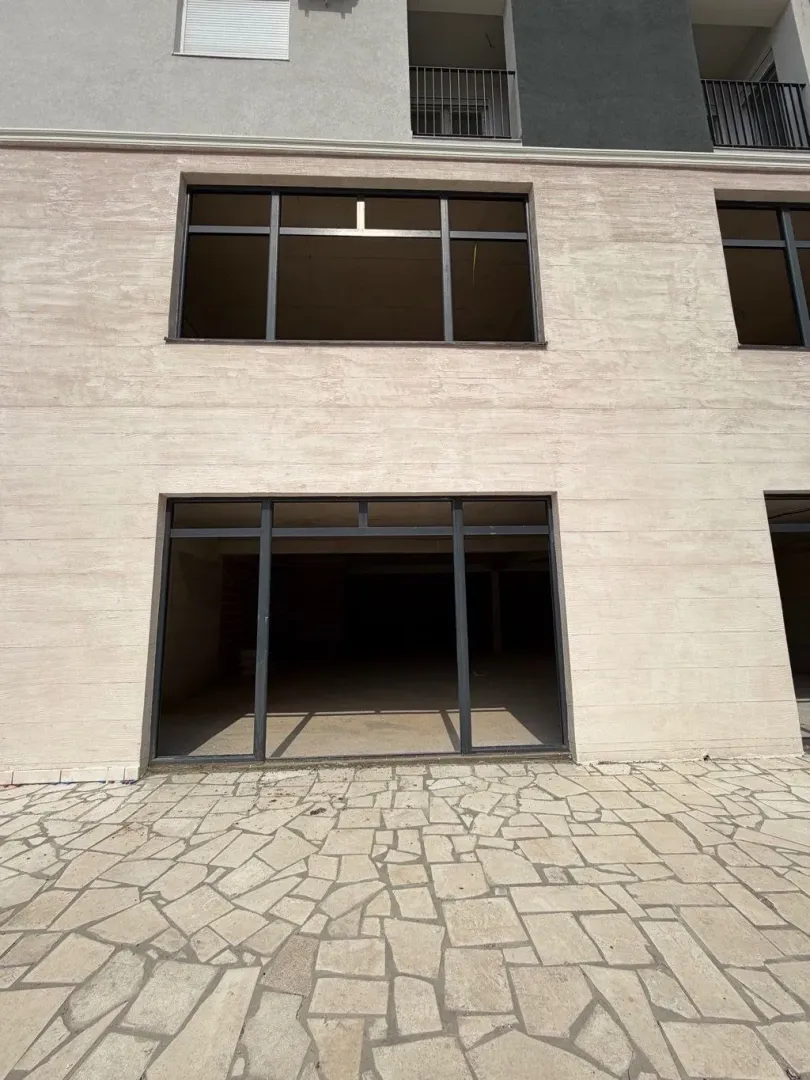 Exterior of a commercial space with large glass portals and a paved courtyard.