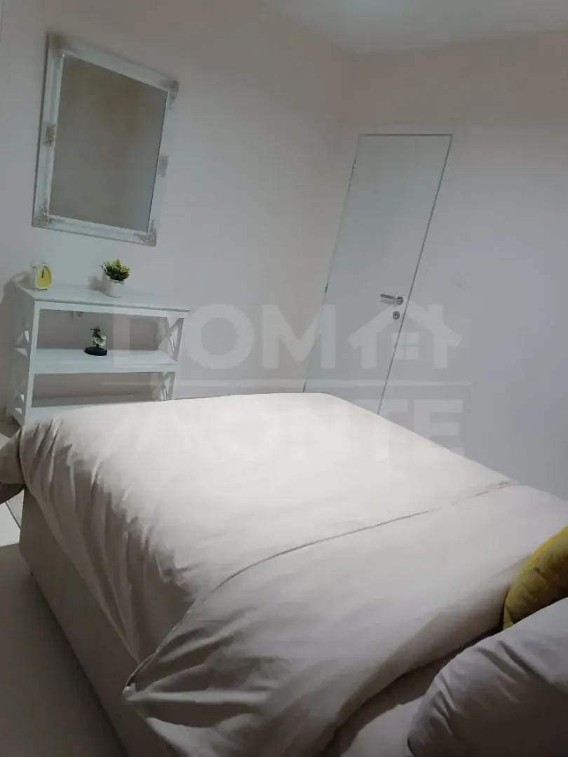 Furnished bedroom with a double bed, dresser, and mirror.