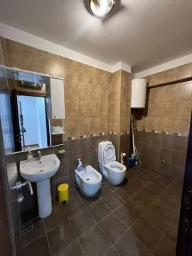 A bathroom with beige tiles, a sink, a bidet, and a toilet. - image 7