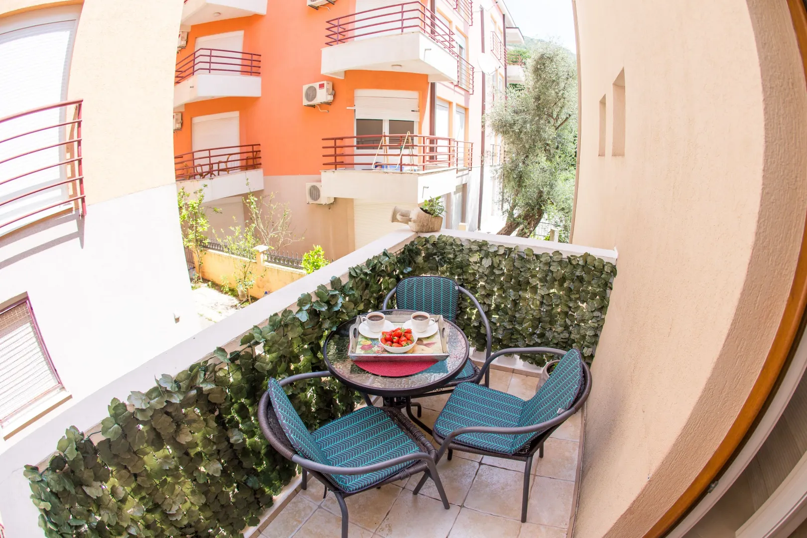 Furnished balcony with seating set and view of surrounding buildings.
