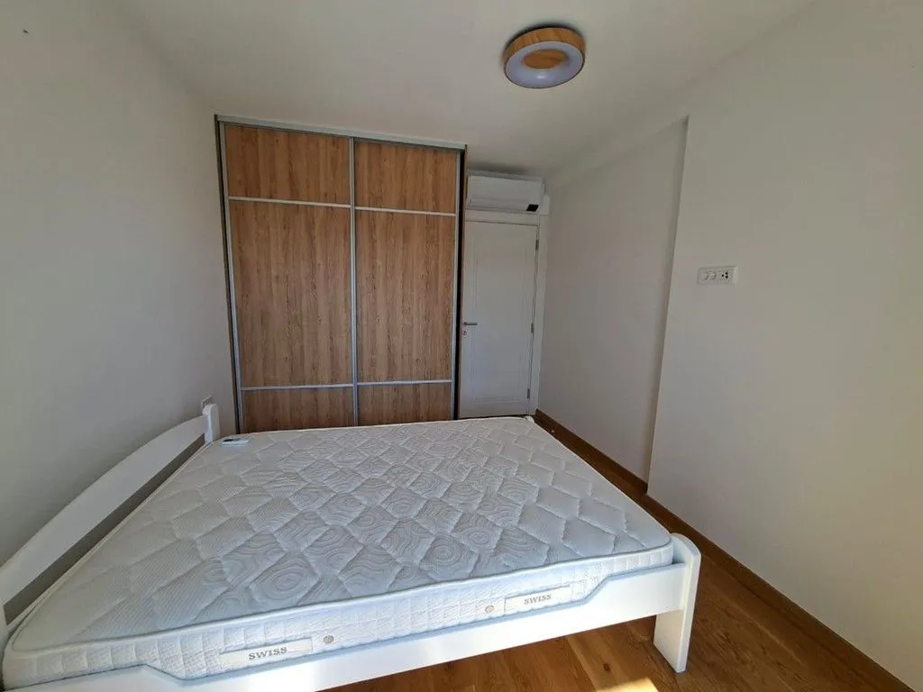 Manja spavaća soba sa krevetom, ugradnim ormarom i klima uređajem.