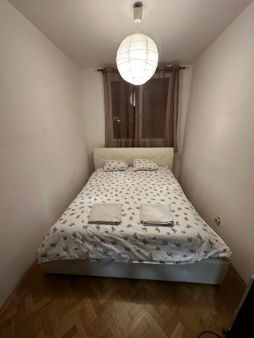 Manja spavaća soba sa bračnim krevetom i prozorom.