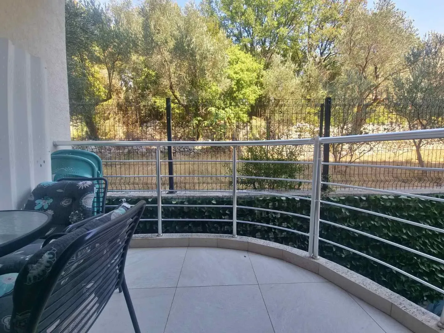 Furnished balcony with a view of the courtyard and greenery.