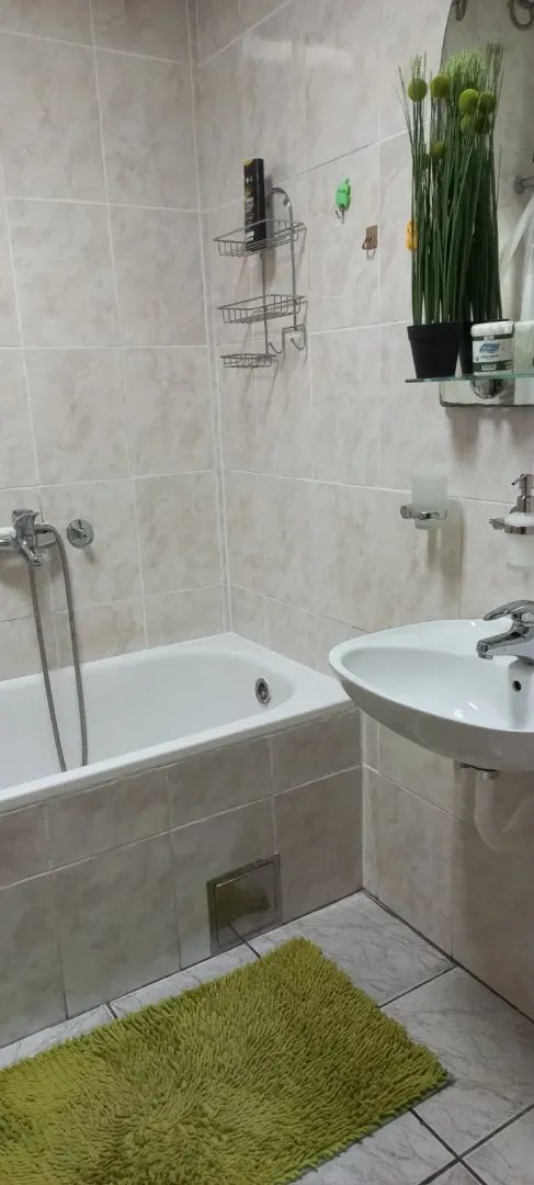 Small bathroom with a bathtub, sink, and ceramic tiles.