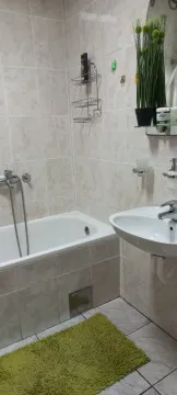 Small bathroom with a bathtub, sink, and ceramic tiles. - image 5