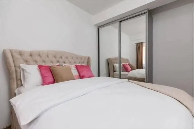 Furnished bedroom with a double bed and a fitted wardrobe with a mirror.