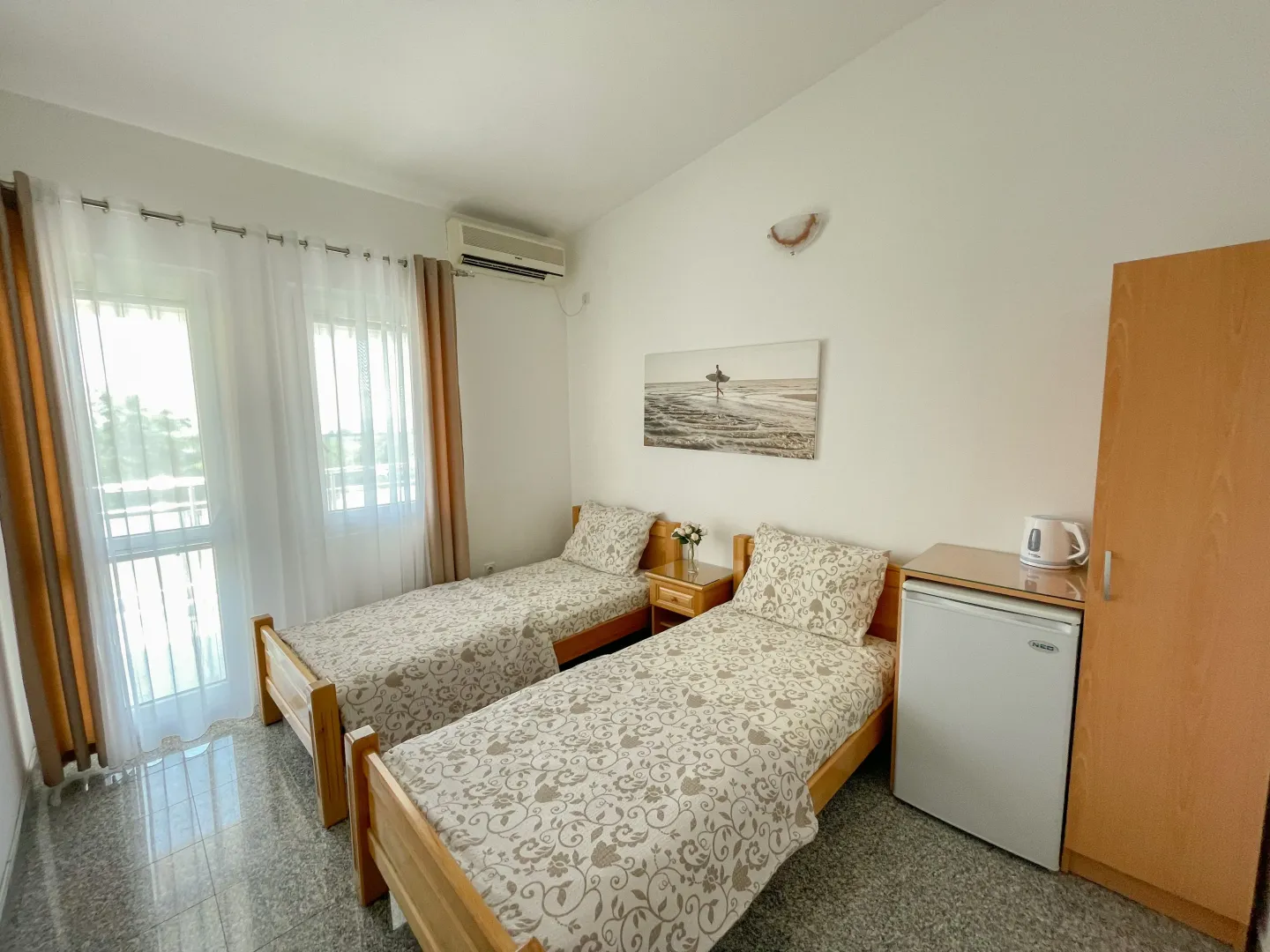 Bedroom with two single beds, a wardrobe, and balcony doors.