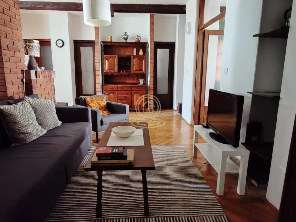 Living room with a sofa, TV, and wooden furniture.