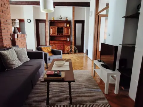 Living room with a sofa, TV, and wooden furniture. - image 2