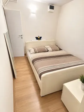 Manja spavaća soba sa bračnim krevetom, belim vratima i parketom na podu. - image 3