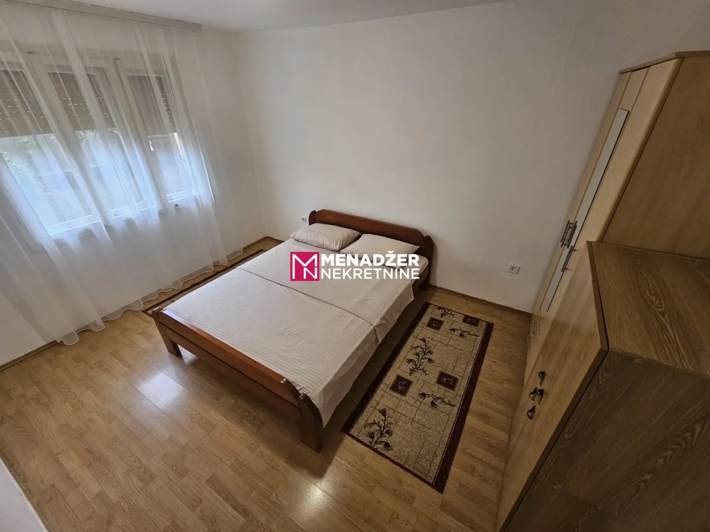 Furnished bedroom with a double bed, wardrobe, and wooden flooring.