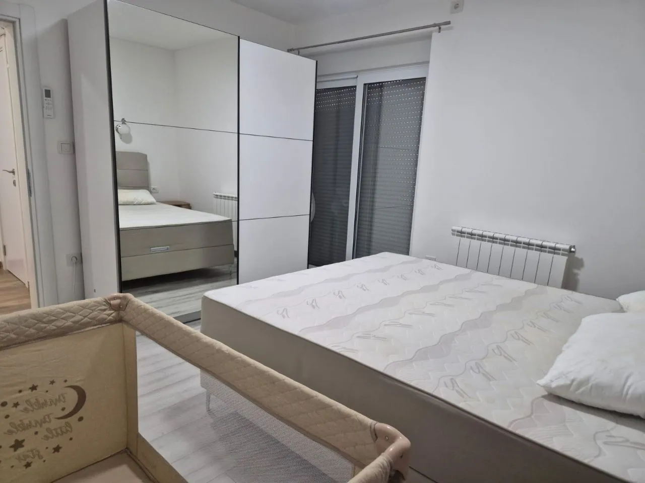 Bedroom with a double bed, a large wardrobe, and a baby cot.