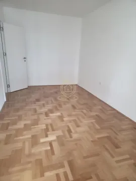 Prazna soba sa belim zidovima i parketom na podu. - image 4