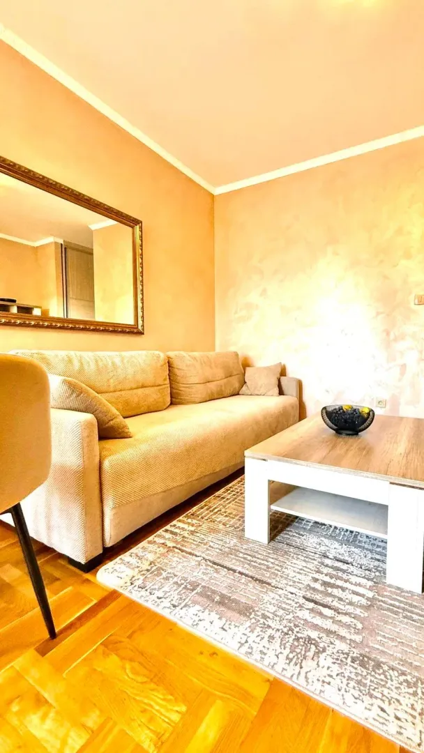 Living room with a beige sofa, coffee table, and a wall mirror.