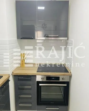 Small kitchen with grey cabinets and a built-in oven.