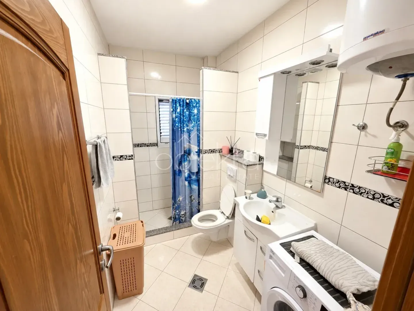 Kupatilo opremljeno umivaonikom, WC šoljom, tuš kabinom i veš mašinom.