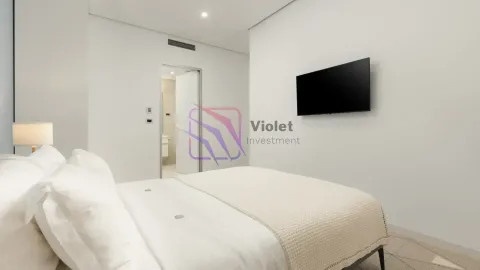 Moderna spavaća soba sa bračnim krevetom, zidnim televizorom i pogledom na kupatilo. - image 8