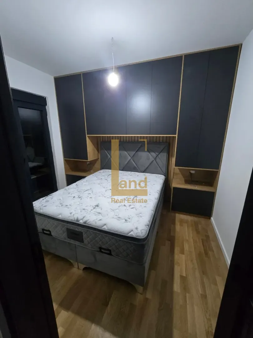 Moderna spavaća soba sa bračnim krevetom i ugradnim ormarima.
