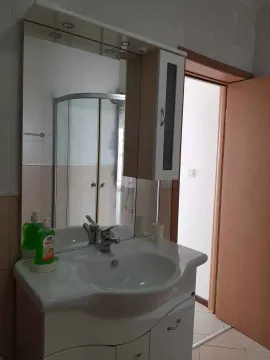 Small bathroom with a sink, mirror, and shower cabin. - image 8