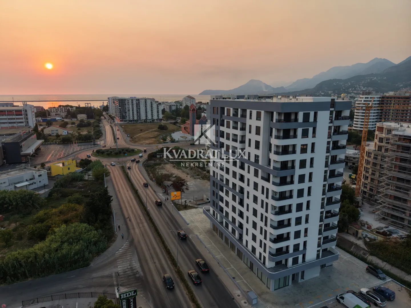 Aerial view of a modern residential building and the surrounding street during sunset.