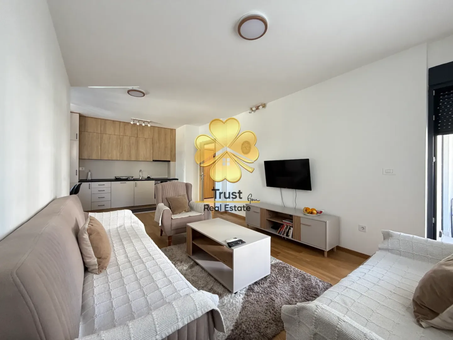 Living room connected to the kitchen in bright tones with furniture.