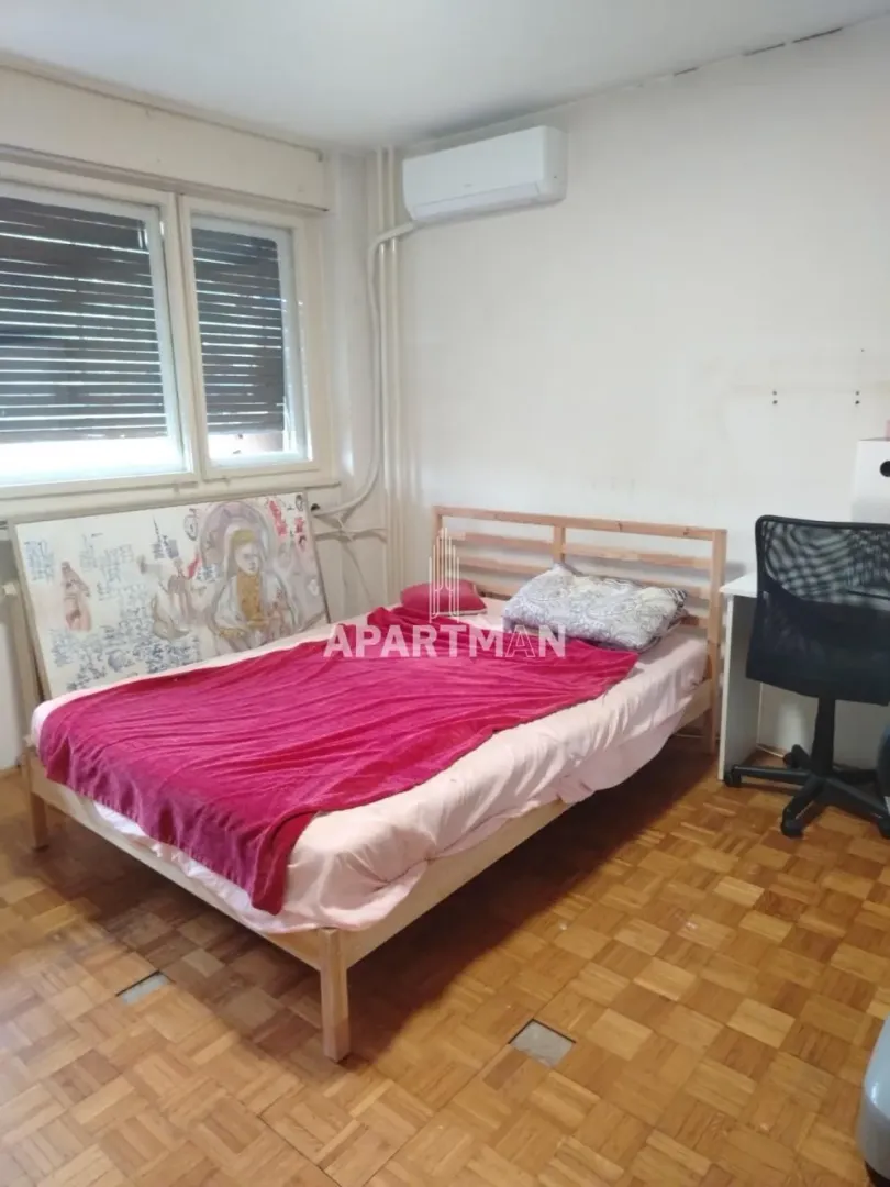 Spavaća soba sa krevetom, radnim stolom i klima uređajem.