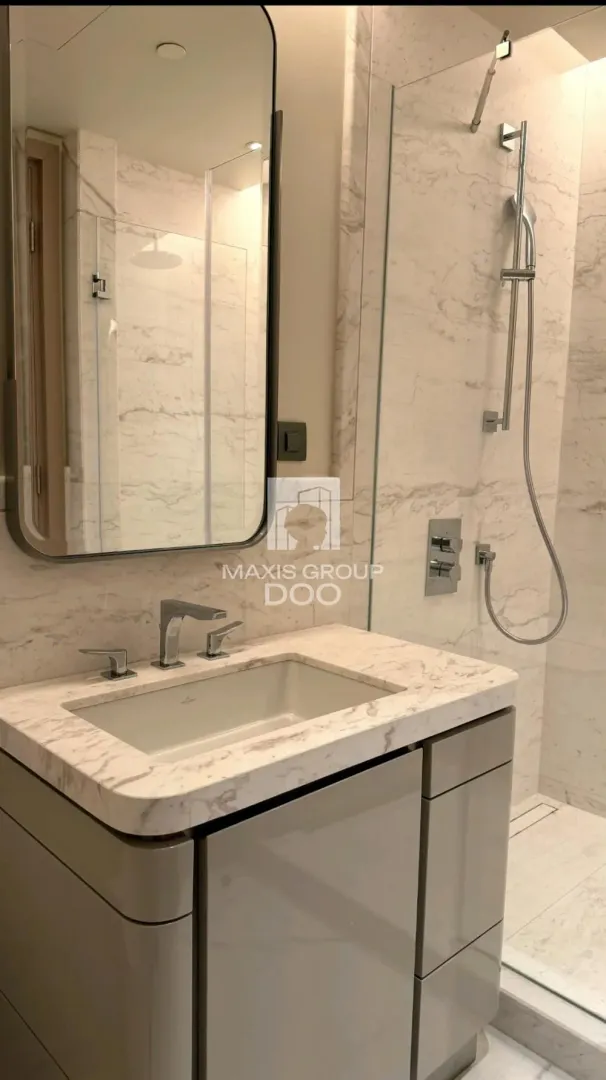 Modernly equipped bathroom with a marble-clad sink and walk-in shower.