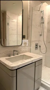 Modernly equipped bathroom with a marble-clad sink and walk-in shower. - image 6
