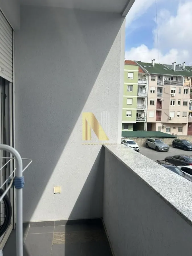 Pogled sa balkona na okolne zgrade i parking.