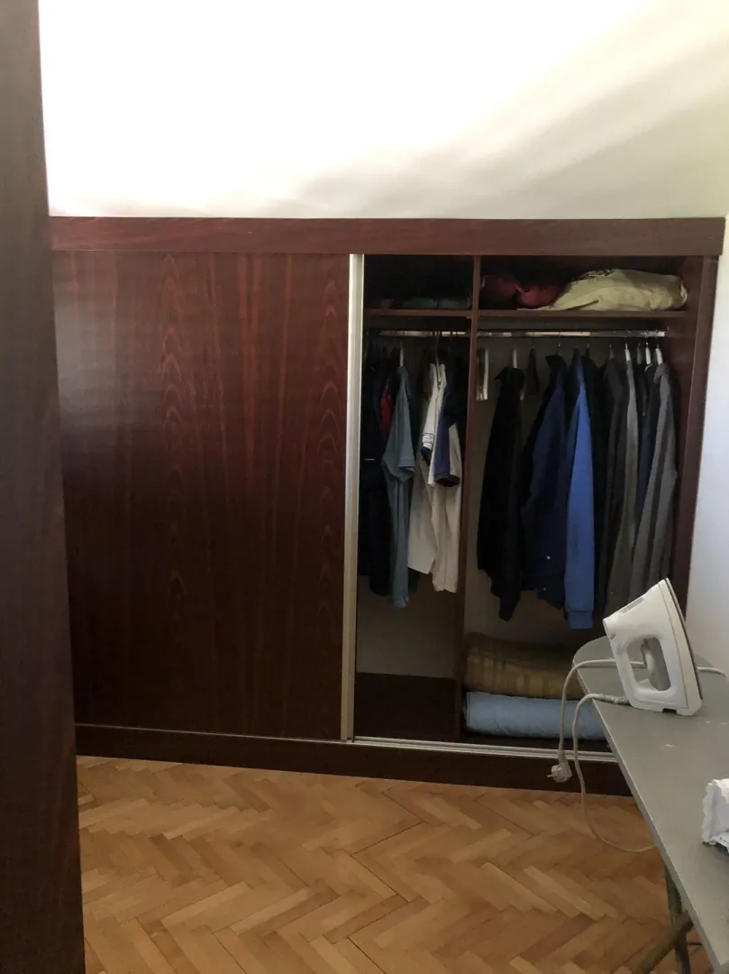 Built-in wooden wardrobe with sliding doors in a bedroom.