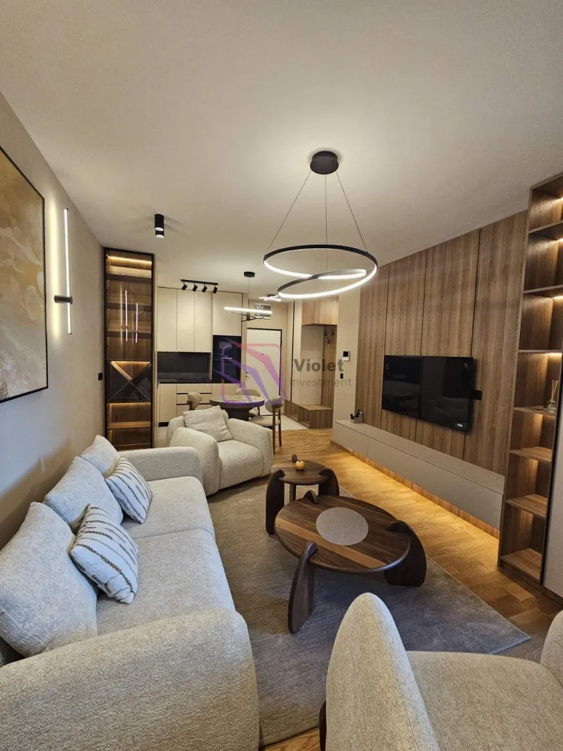 Modern living room with a sofa, TV, and dining area in the background.