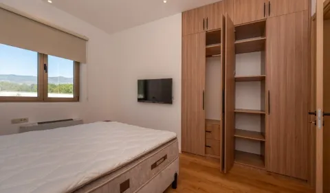 Bedroom with a bed, a large wooden wardrobe, and a wall-mounted TV. - image 7