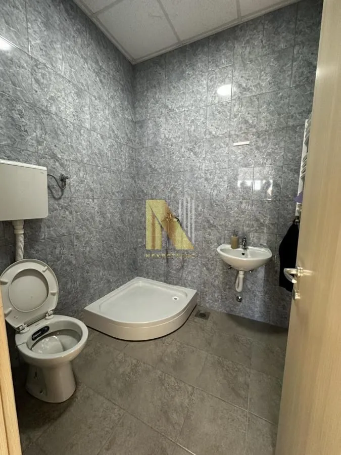 Smaller bathroom with a shower cabin, washbasin, and toilet bowl tiled with ceramic tiles.
