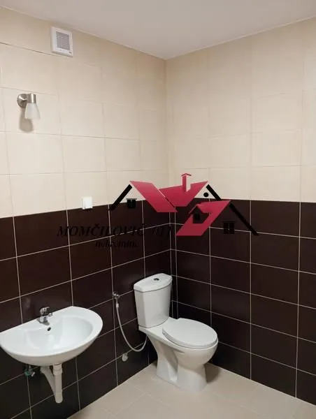 Smaller bathroom with a sink and a toilet, tiled with ceramic tiles.
