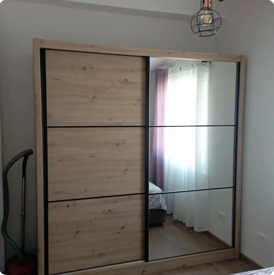 Spavaća soba sa velikim garderoberom sa kliznim vratima i ogledalom.