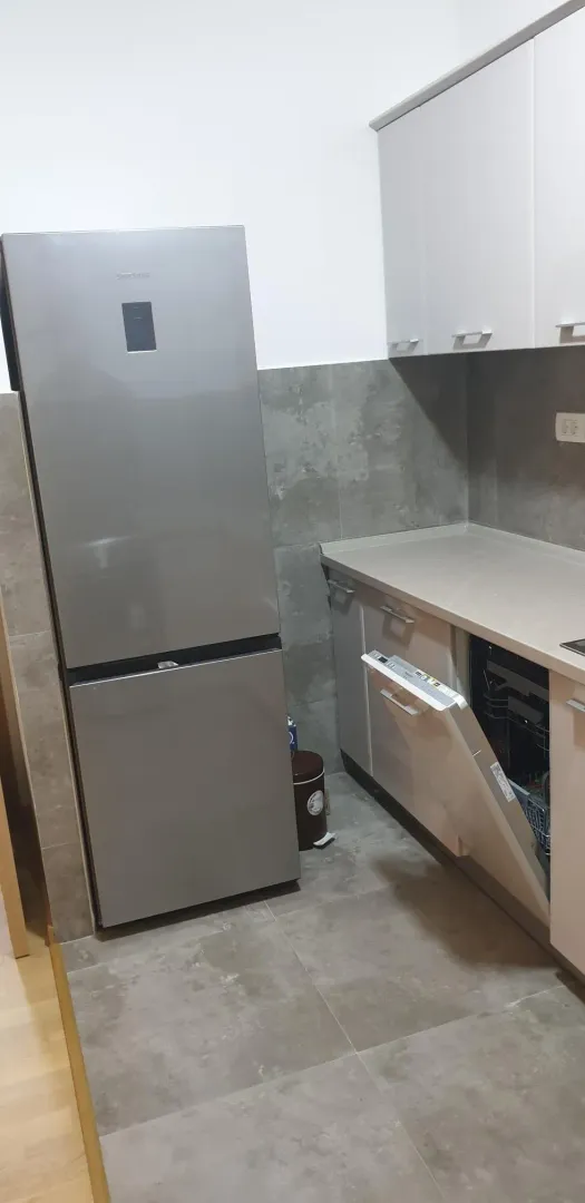 Kuhinjski ugao sa modernim sivim frižiderom i ugradnim elementima.