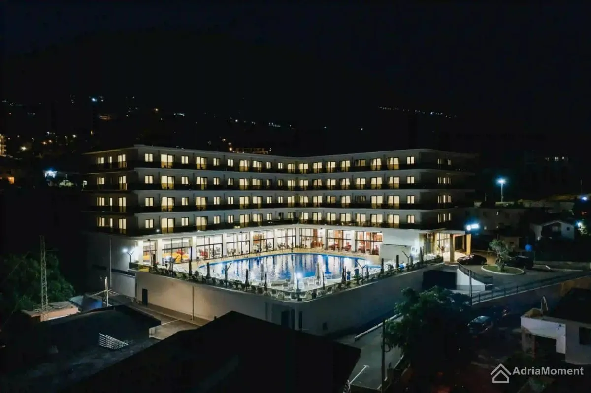 Night view of the illuminated hotel complex with a swimming pool.